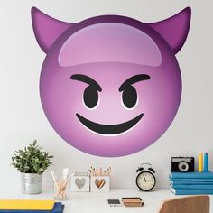 a wall sticker with an evil smiley face on it's side, next to a desk