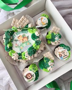 some cupcakes are in a box with green ribbons around them and decorated like animals