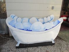 a white tub filled with lots of blue balls sitting on top of a gravel ground