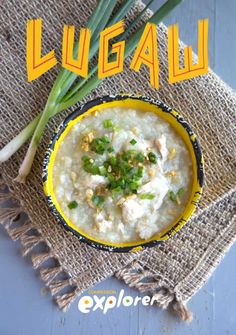 a yellow bowl filled with food on top of a table next to some green onions