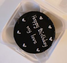 a black cake with white frosting on it in a box that says happy birthday to you