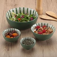 four bowls filled with food sitting on top of a wooden table