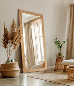 a large mirror sitting on top of a wooden floor next to a chair and potted plant