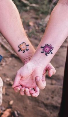 two people holding hands with small tattoos on their wrist and arm, one has a monkey