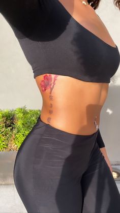 a woman in black sports bra and leggings with tattoos on her stomach,