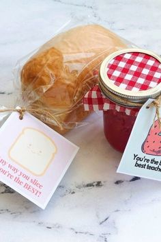 there is a jar of jam and some bread on the table next to each other