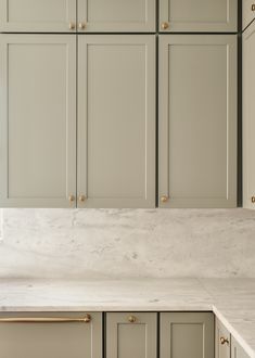 an empty kitchen with marble counter tops and gold pulls on the cabinet doors, along with brass knobs