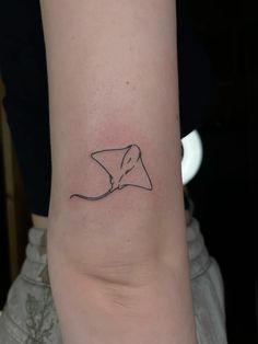 a woman's arm with a small tattoo of a manta ray on it