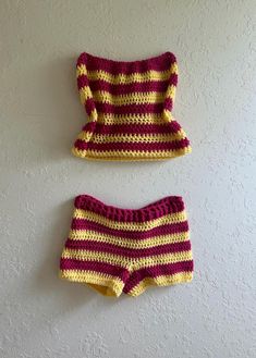 two pieces of crocheted clothing are hanging on the wall next to each other