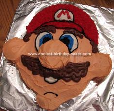 a birthday cake made to look like mario's face on tin foil with a mustache