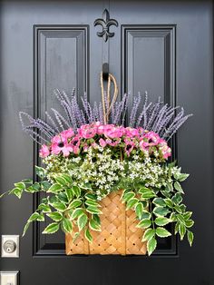 a basket filled with pink and white flowers sitting on top of a black door frame