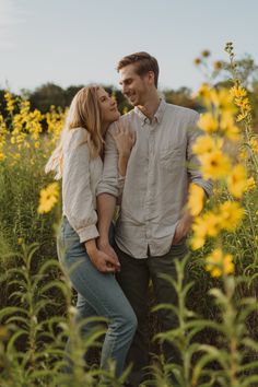 a man and woman are standing in the middle of a field full of yellow flowers