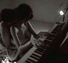 two women sitting next to each other in front of a piano with their hands on the keys