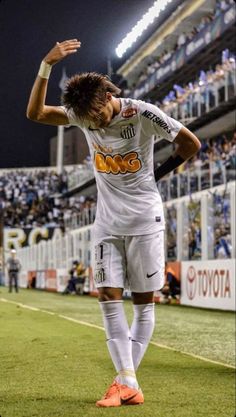 a man standing on top of a soccer field holding his hand up in the air