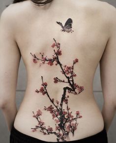 the back of a woman's body with flowers and a butterfly tattoo on it