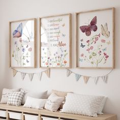 three framed pictures hang on the wall above a wooden bench with pillows and pillow cases