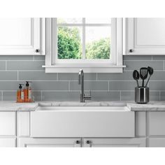 a kitchen sink with utensils on the counter and a window in the background