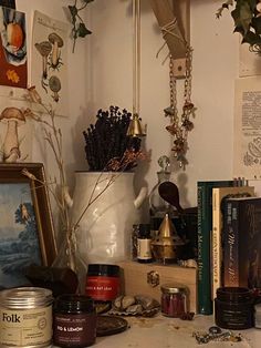 an assortment of items are displayed on a shelf in the corner of a room, including candles and books