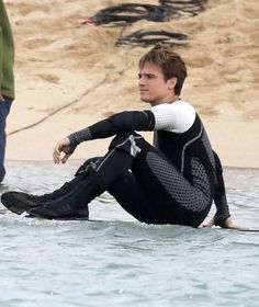 a man sitting on top of a surfboard in the ocean next to another man