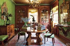 an ornate dining room with green walls and wooden furniture is featured in this image, along with a chandelier that hangs from the ceiling