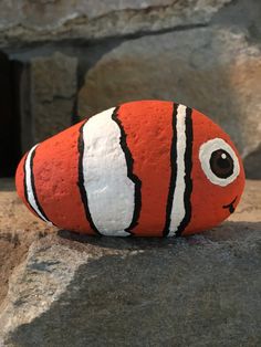 an orange and white striped fish sitting on top of a rock