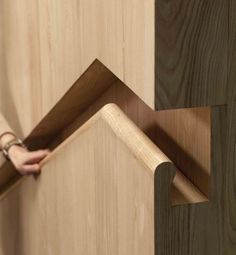 a person is opening the corner of a wooden door