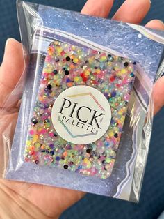 a person holding up a plastic bag filled with lots of different colored sprinkles