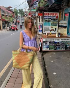 a woman is standing on the sidewalk holding a basket