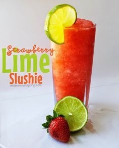 a strawberry lime slushie next to a strawberries and lime slice on a white plate