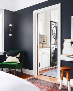 a room with blue walls, white cabinets and a green chair in front of the door