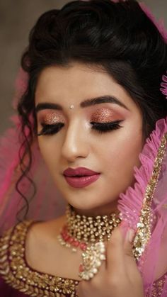 a woman in pink and gold makeup looks at the camera