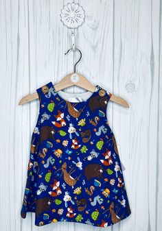 This sweet little woodland print A-line dress buttons at the shoulder and can be worn as a dress or jumper.  The vibrant colors are on the royal blue background add pizazz to the outfit.  The 100% cotton woodland print has bears, deer, owls, frogs, racoons, foxes, beavers,  bunnies, mice, turtles in a field of mushrooms...did I name them all?   So cute! The dress is fully lined in a light weight white Imperial Batiste.   Perfect little summer dress for a day at the beach, play date, first birthd Cute Blue Dresses With Buttons, Cute Blue Dress With Buttons, Blue Fall Playtime Dress, Blue Dress For Playtime In Fall, Field Of Mushrooms, Summer Sun Dress, Royal Blue Background, Woodland Print, I Name