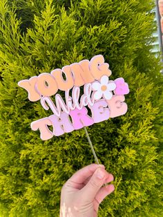 a person holding up a pink and white cake topper with the words you're sweet on it