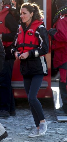 a woman in a red life jacket is walking near other people wearing life jackets and water vests