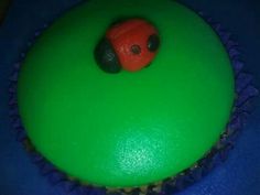 a green cupcake with a red ladybug on top