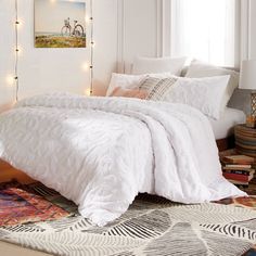 a bed with white comforter and pillows in a room decorated with books, rugs and lights