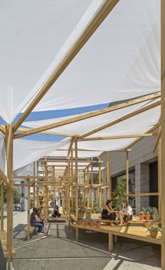 several people sitting on wooden benches under an awning