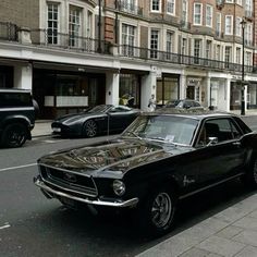 an old car parked on the side of the road in front of some tall buildings