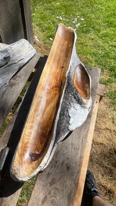 a large wooden bowl sitting on top of a wooden bench next to a grass field