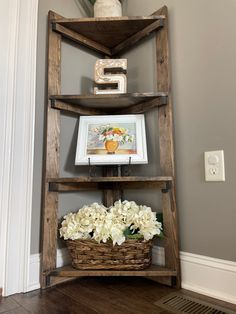 a wooden shelf with flowers and pictures on it next to a light switch in a room