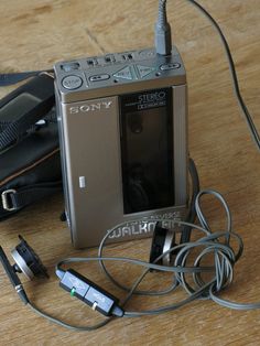 an electronic device sitting on top of a wooden table next to ear buds and headphones