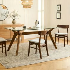 a dining room table with chairs and a rug on the floor in front of it