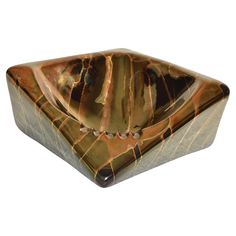 a brown and black marble bowl sitting on top of a white surface with an intricate design