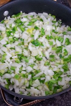 onions and celery are being cooked in a pan on the stove top with tongs