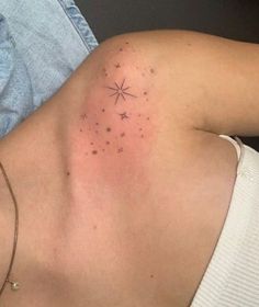 the back of a woman's shoulder with small stars on her left arm and chest