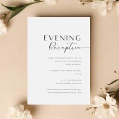 an elegant wedding reception card with white flowers and greenery on the bottom right corner