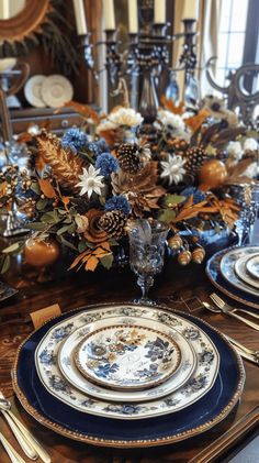 the table is set with blue and white plates, silverware, and gold accents