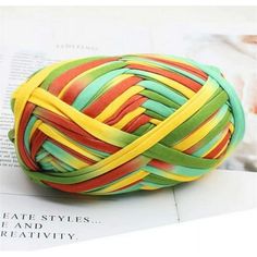 a ball of colorful yarn sitting on top of a white table next to a book