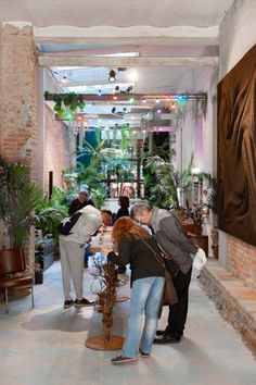 several people are standing in a room with plants