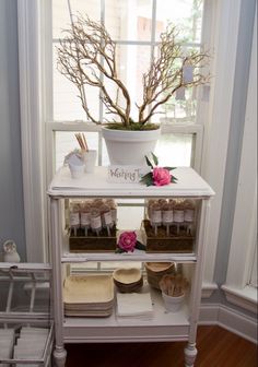 a white shelf filled with lots of items next to a window